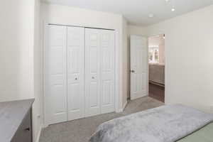 Bedroom featuring neutral-toned walls, gray carpet flooring, and a bi-fold closet with white panel doors