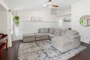Living area featuring rich wood-finish flooring, white board and batten wall detailing, and a modern ceiling fan