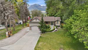 Traditional-style residence featuring a two-car garage, concrete driveway, and established landscaping