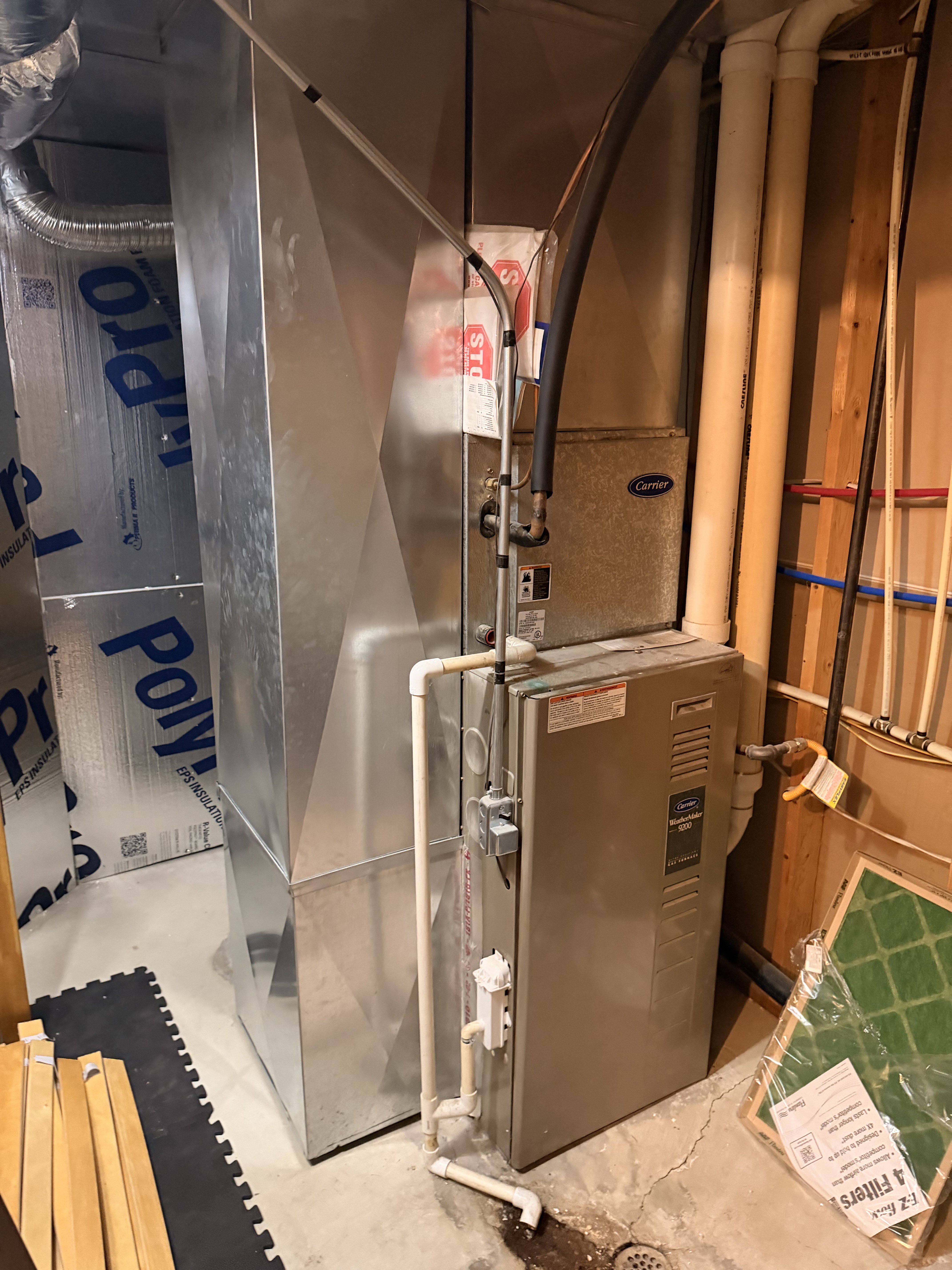 Furnace and ductwork system featuring a Carrier brand unit, PVC piping, and galvanized sheet metal ducts