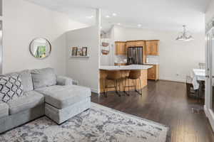 Open-concept living area featuring wood-finish flooring, vaulted ceilings, and recessed lighting