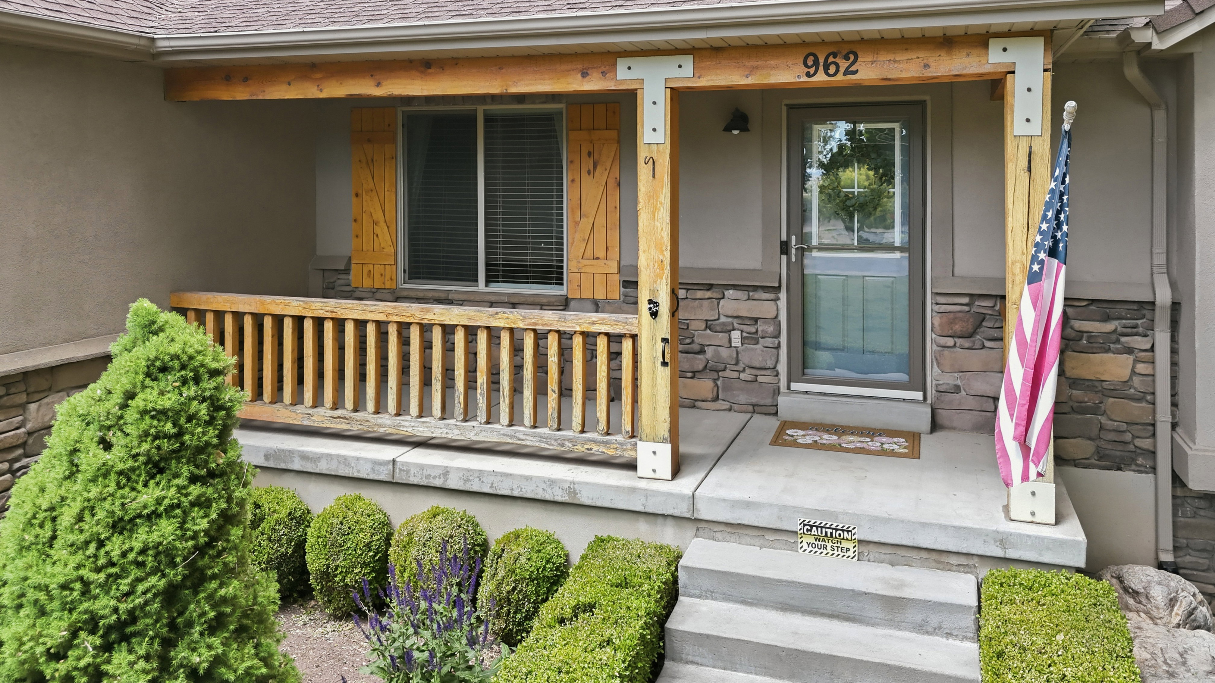 Covered front porch featuring rustic wood columns and railing