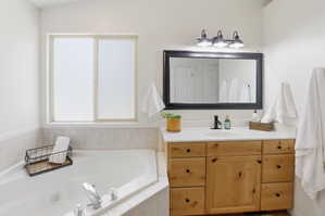 Bathroom featuring a wood-finish vanity with a single sink and white countertop, framed mirror, and three-light vanity fixture