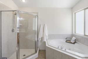 Corner soaking tub with integrated tiled surround, frosted window, and adjacent glass-enclosed shower featuring a tiled interior and built-in shelf