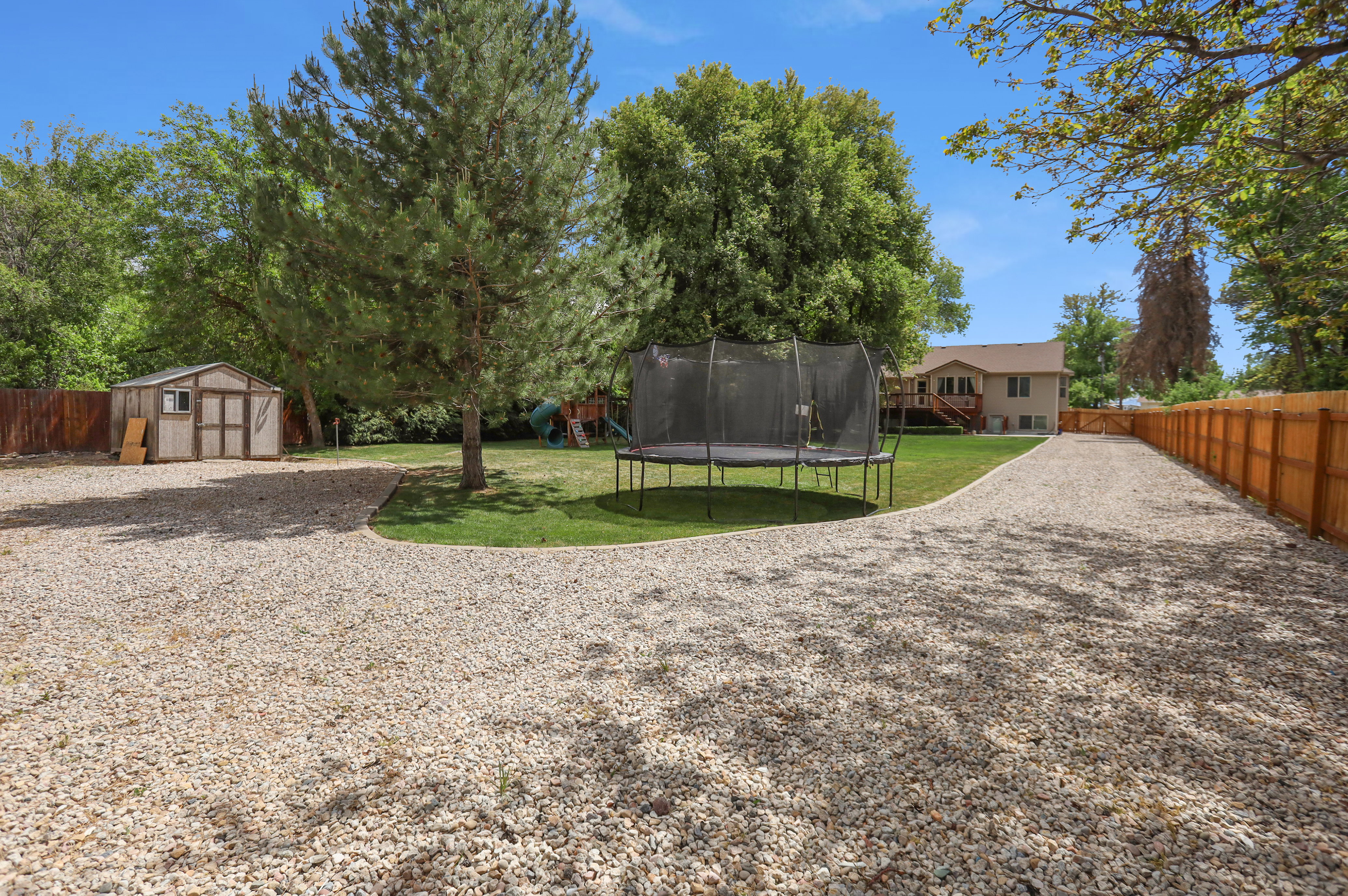Expansive gravel driveway bordered by a wooden privacy fence