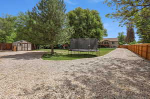 Expansive gravel driveway bordered by a wooden privacy fence