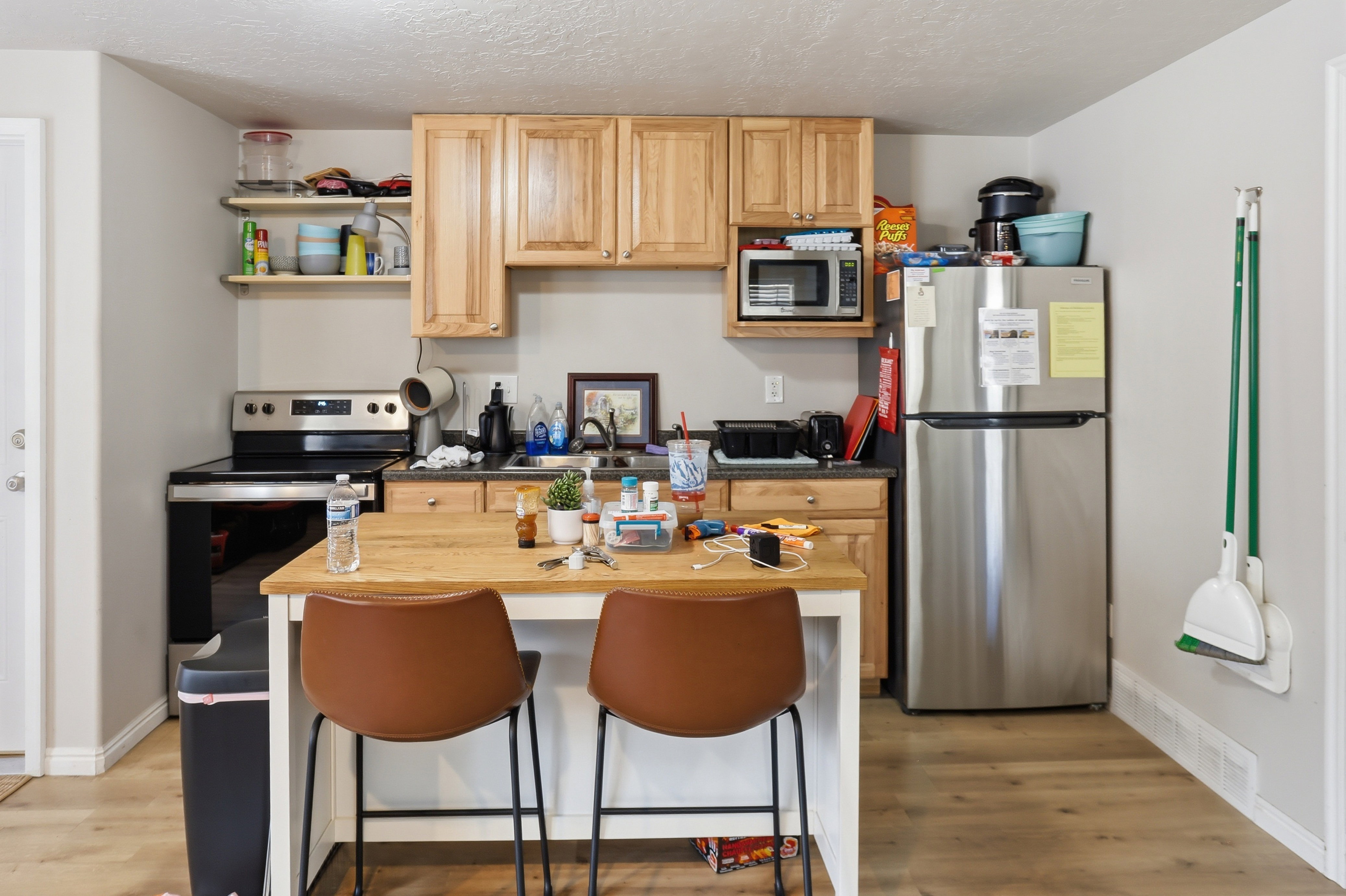 Kitchen featuring wood-finish flooring, natural wood cabinetry, stainless steel appliances, and a central island with seating