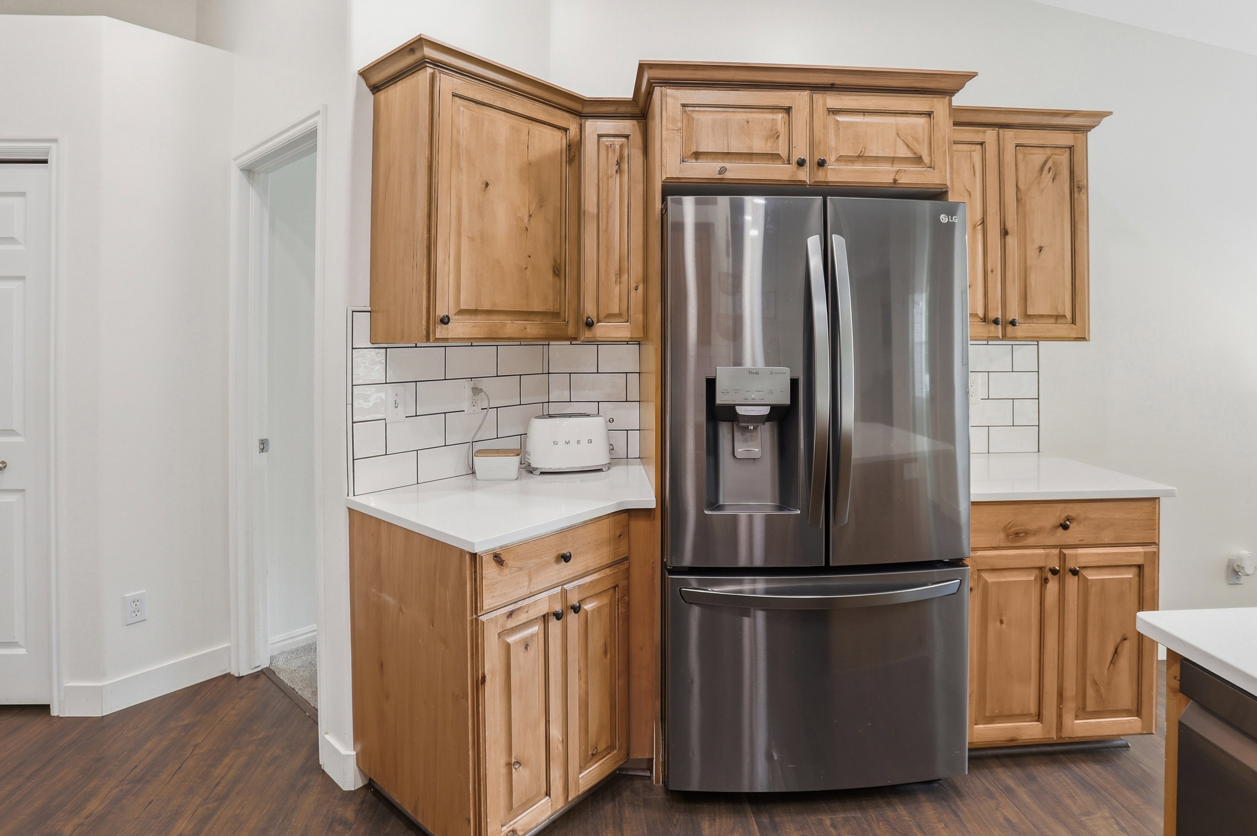 Kitchen area featuring wood cabinetry, white countertops, and a subway tile backsplash