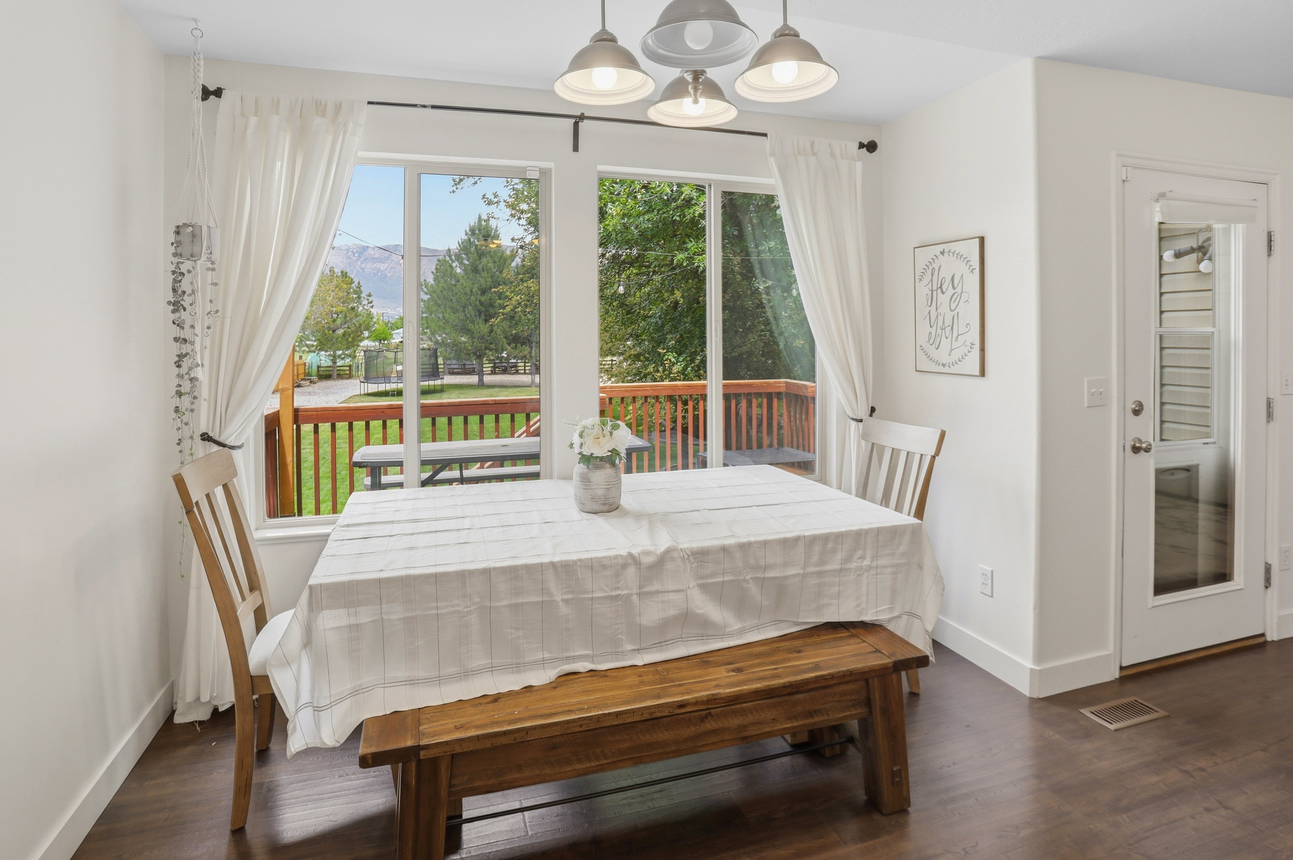 Dining area featuring large windows overlooking a wooden deck and mountain scenery