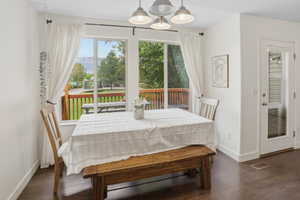 Dining area featuring large windows overlooking a wooden deck and mountain scenery