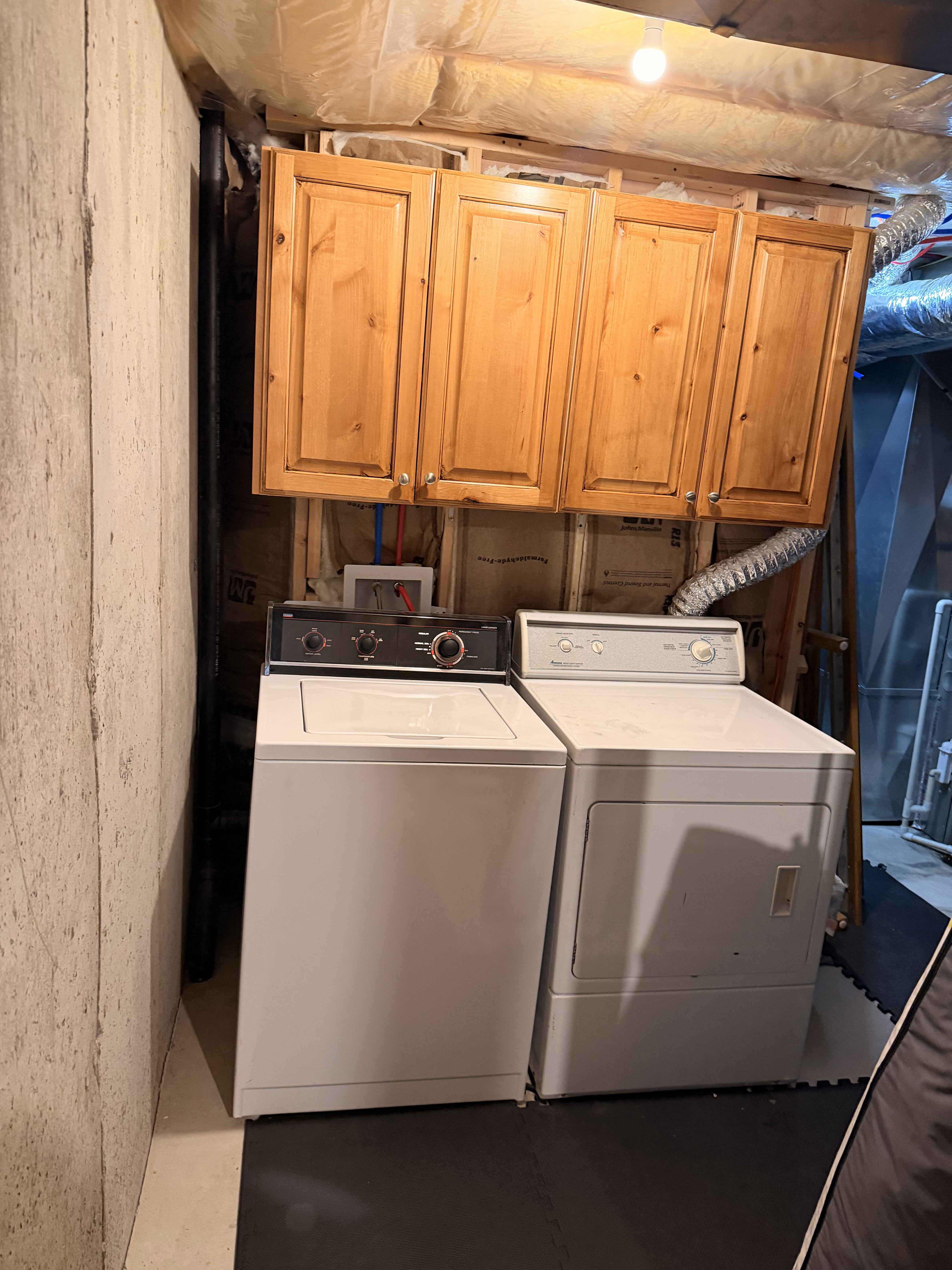 Utility area featuring wood cabinetry, concrete wall, and insulated ceiling