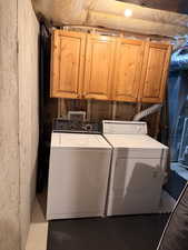 Utility area featuring wood cabinetry, concrete wall, and insulated ceiling