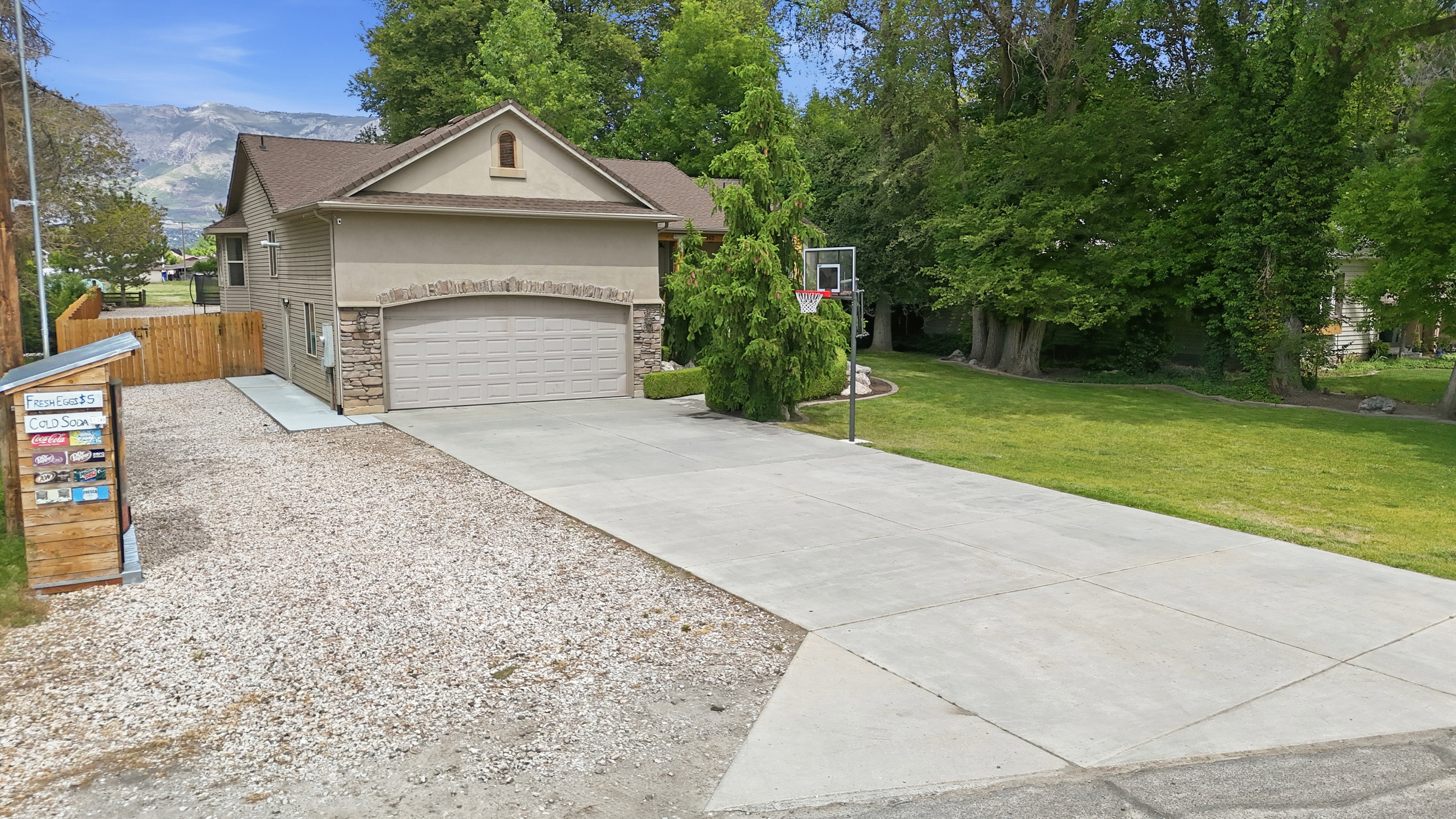 Two-story residence featuring a neutral stucco exterior with stone accents, an attached two-car garage, and a brown shingled roof