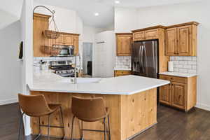Kitchen featuring a spacious island with a white countertop, wood-finish cabinetry, stainless steel appliances, and a subway tile backsplash