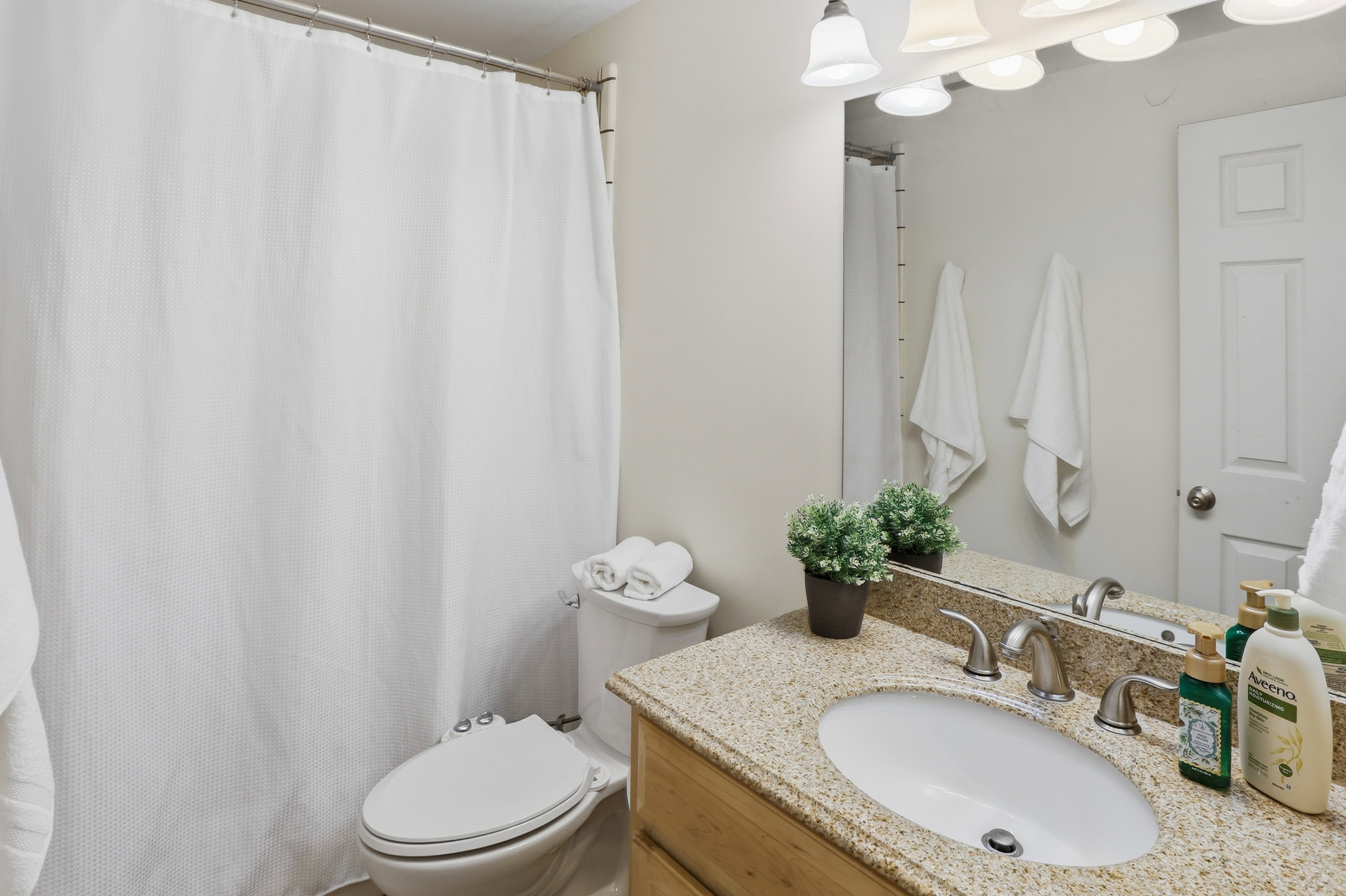 Bathroom featuring a vanity with a light-toned stone countertop, an undermount sink, and a brushed nickel faucet
