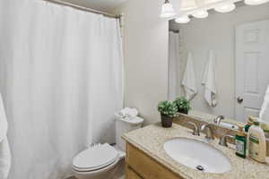 Bathroom featuring a vanity with a light-toned stone countertop, an undermount sink, and a brushed nickel faucet