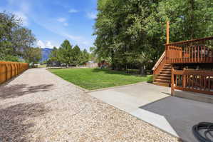 Expansive backyard featuring a large gravel area, manicured lawn, and mature trees