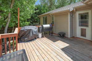 Spacious outdoor wood deck with wood railing, string lights, and a screen door entry to the property