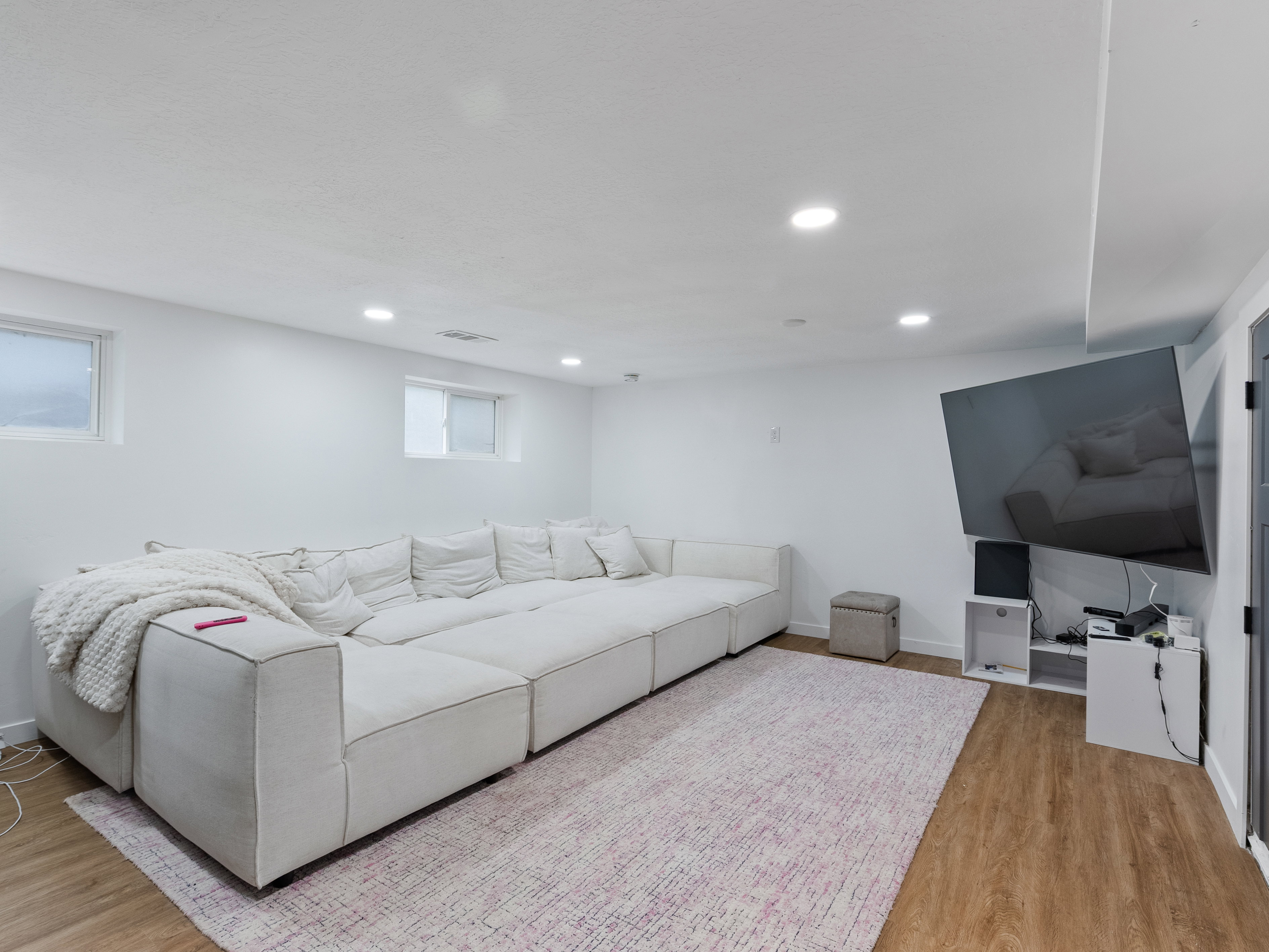 Spacious room featuring wood-finish flooring, recessed lighting, and white walls