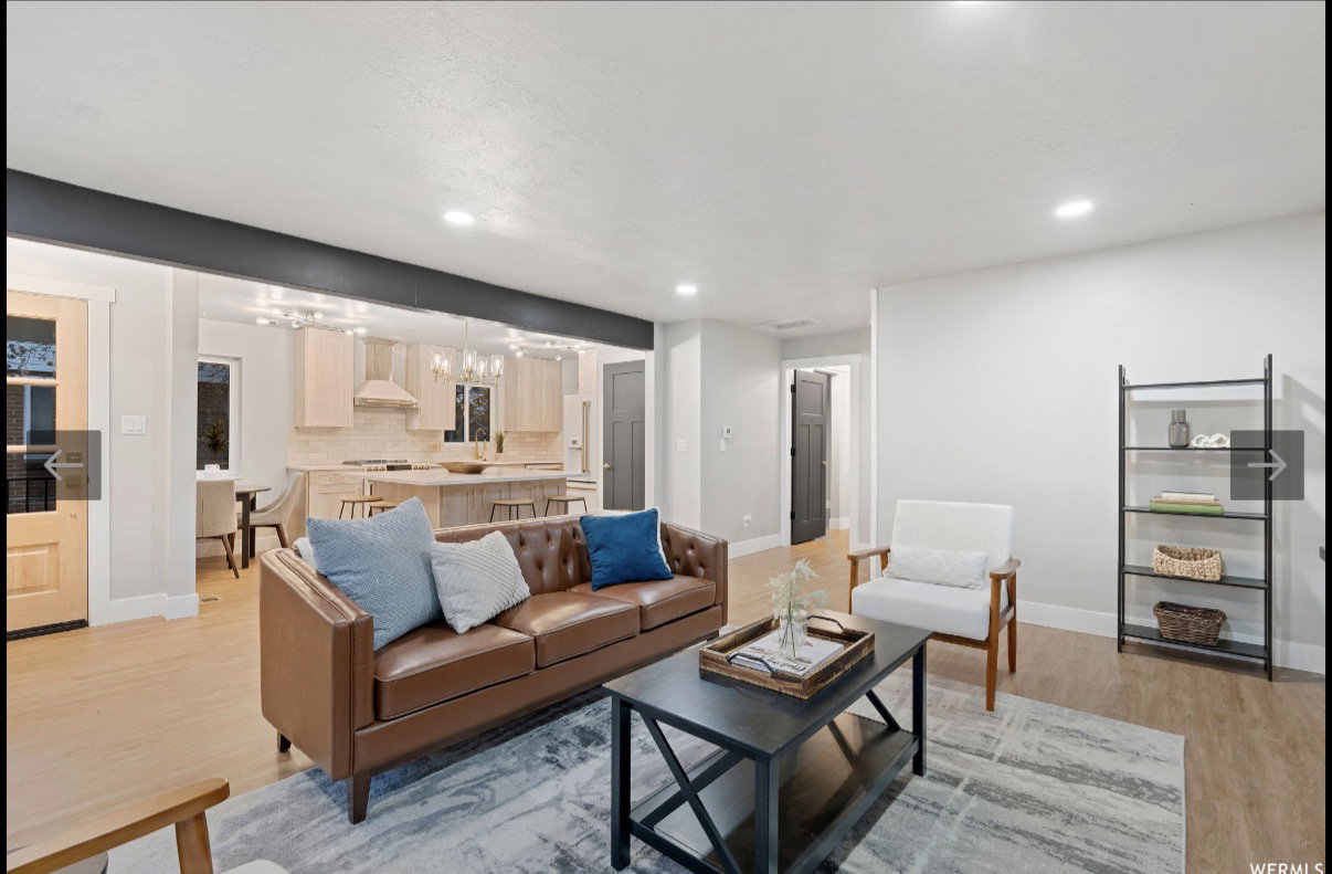 Open-concept living space featuring wood-finish flooring, recessed lighting, and a dark accent beam
