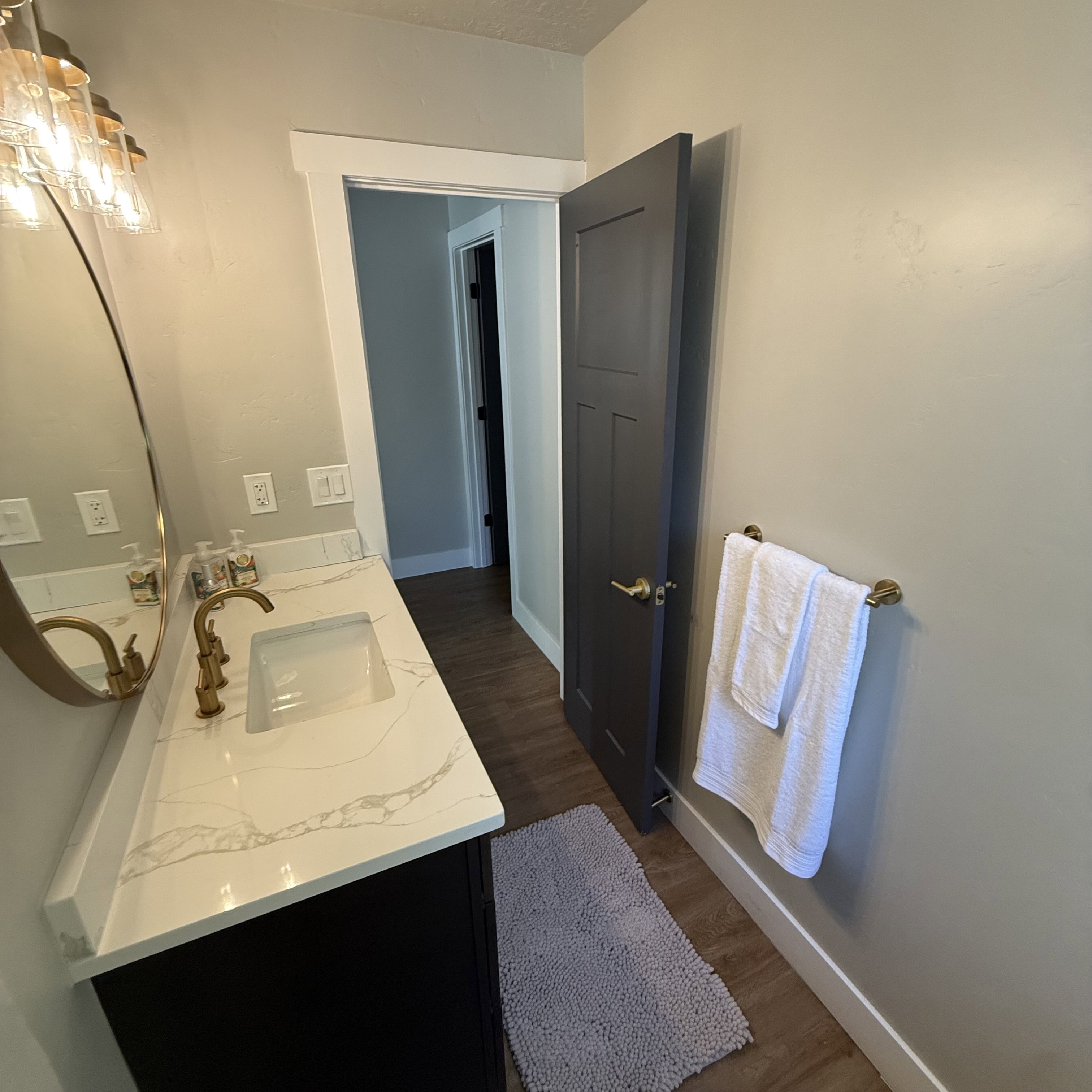 Vanity featuring a white countertop with grey veining, undermount sink, and brass-tone faucet
