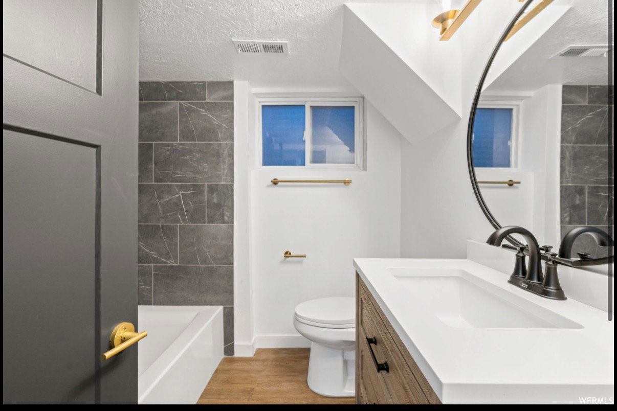 Bathroom featuring a wood-finish vanity with an integrated white sink and dark bronze faucet