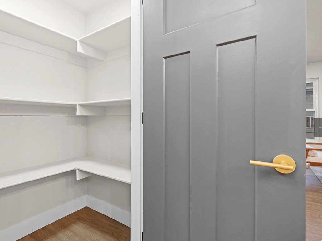 Built-in pantry shelving featuring white finishes and wood-finish flooring