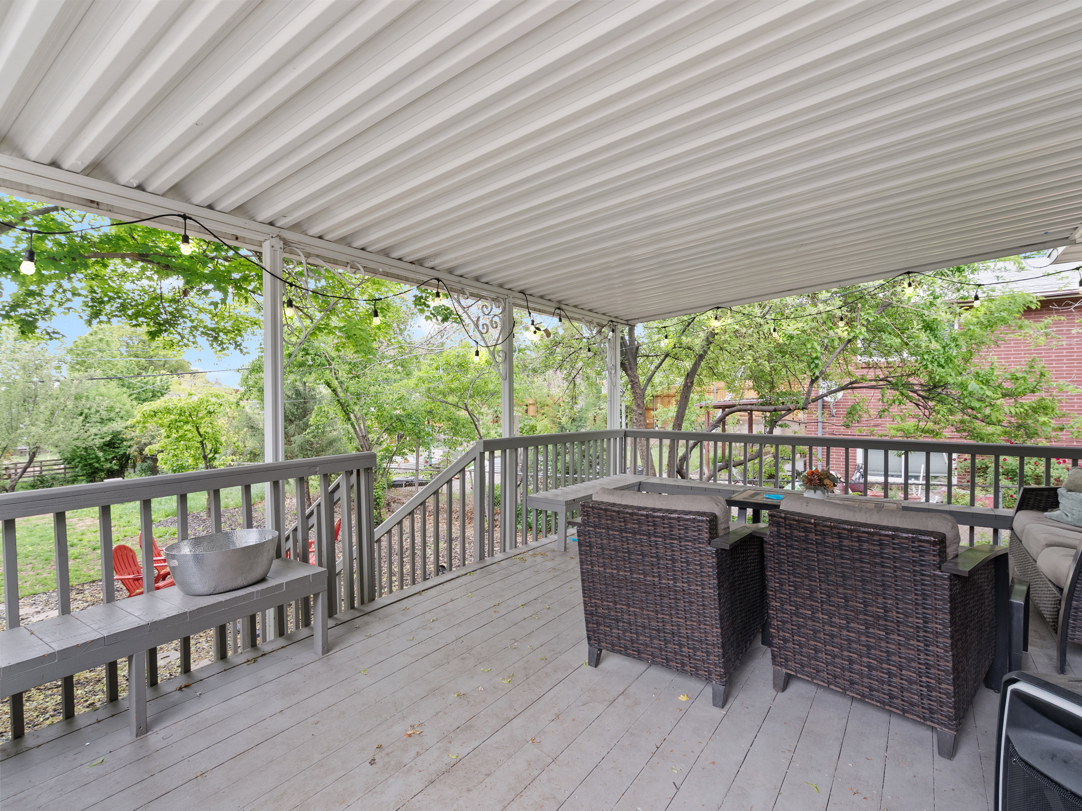 Expansive covered deck featuring wood-finish decking, painted wood railings, and a solid overhead covering