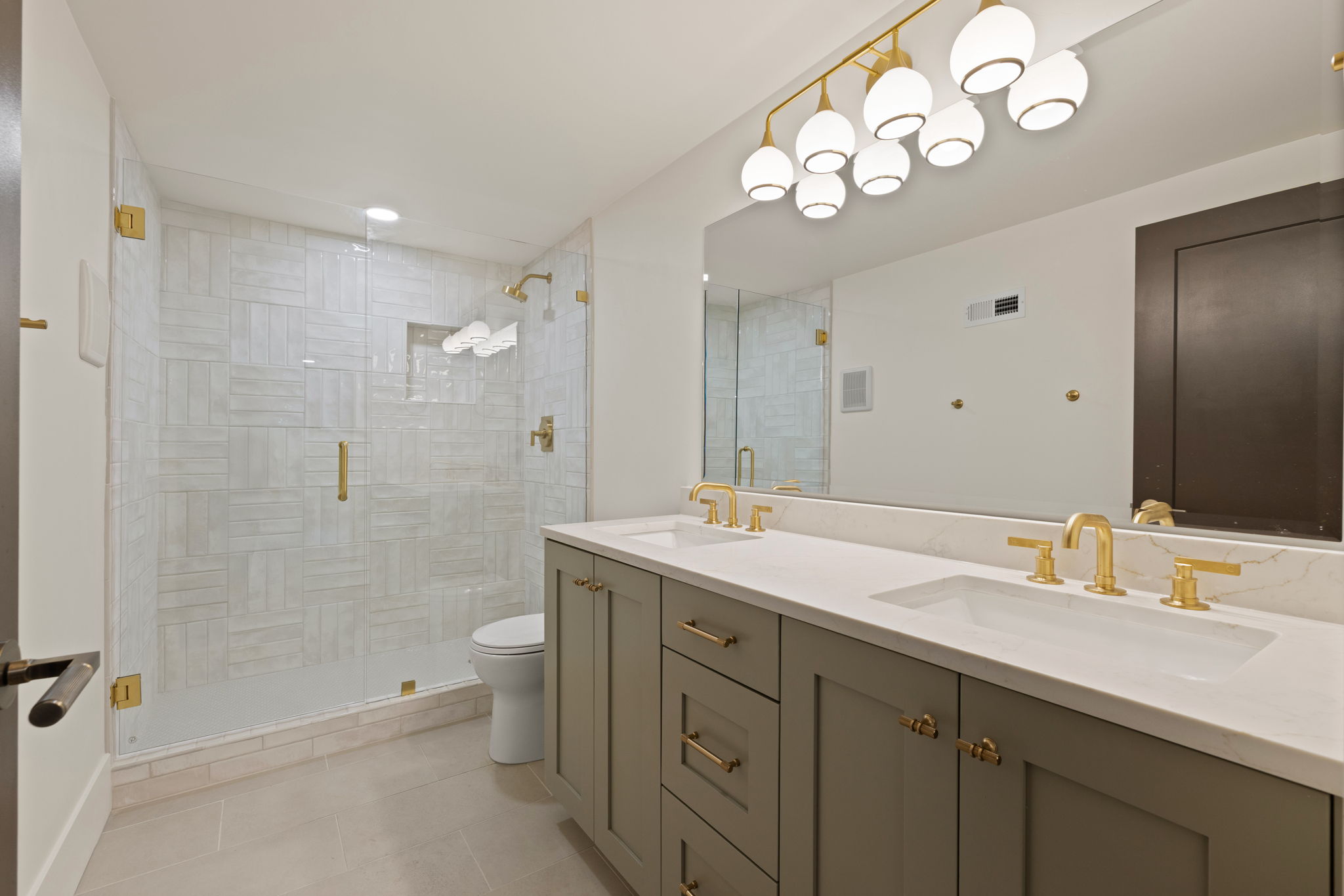 Bathroom featuring a double vanity with stone countertops and brass fixtures
