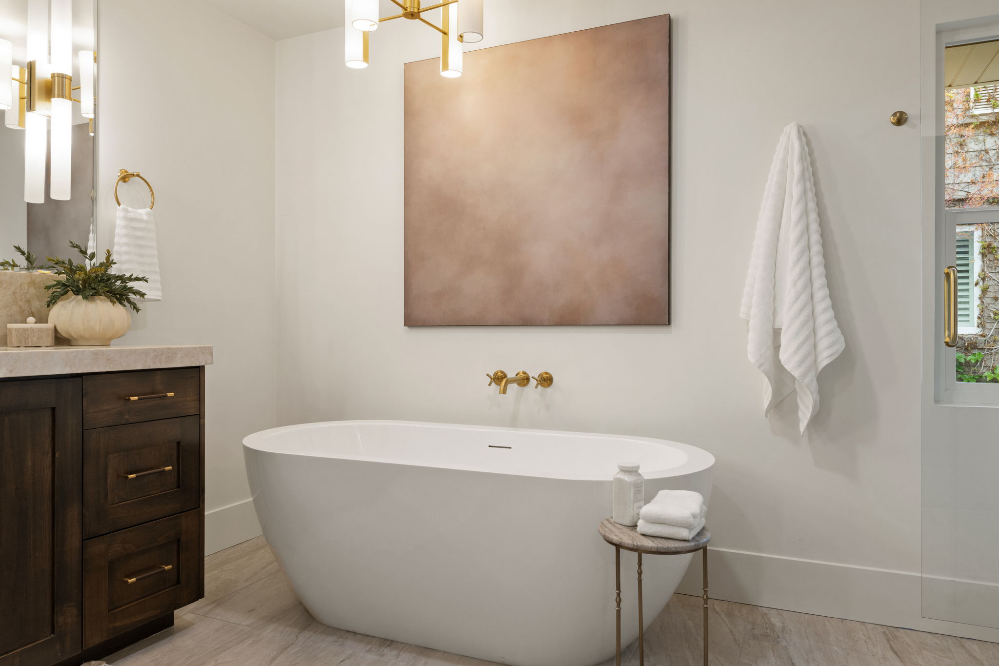Freestanding soaking tub with wall-mounted brass fixtures