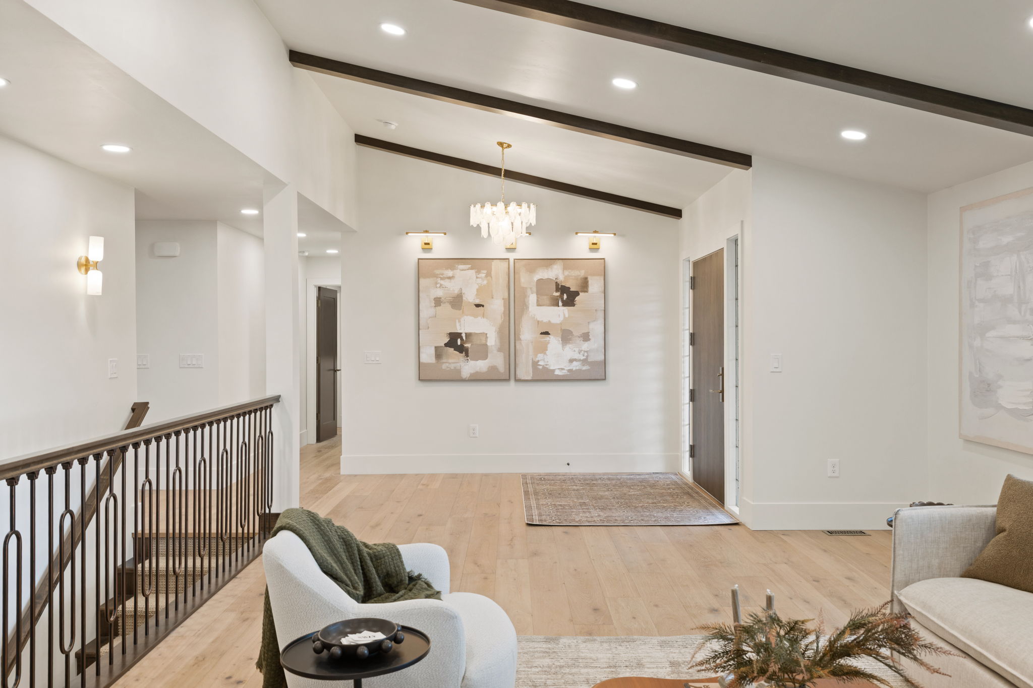 Vaulted ceilings with dark wood beams, light wood-finish flooring, and recessed lighting