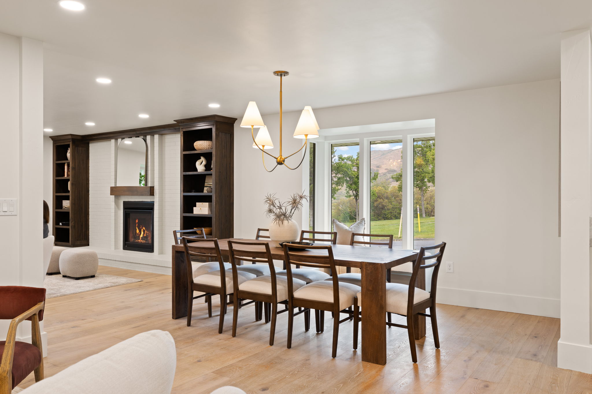 Dining area featuring a contemporary chandelier, large picture window with mountain scenery, and light wood-finish flooring