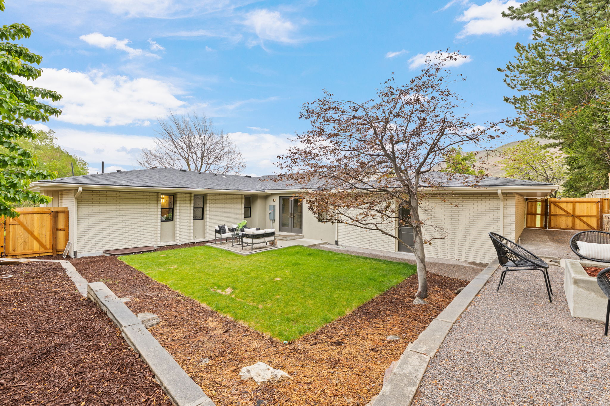 Expansive rear facade featuring brick and stucco siding with a dark asphalt shingle roof