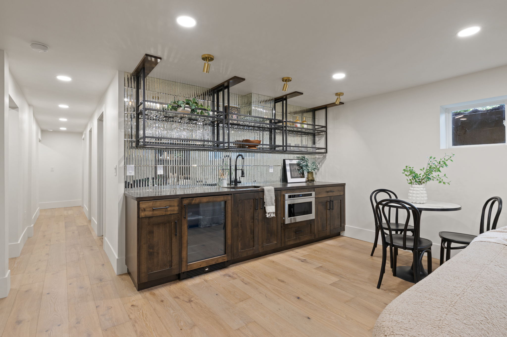Wet bar featuring a dark wood-finish cabinet, integrated beverage refrigerator, stainless steel microwave, and black faucet
