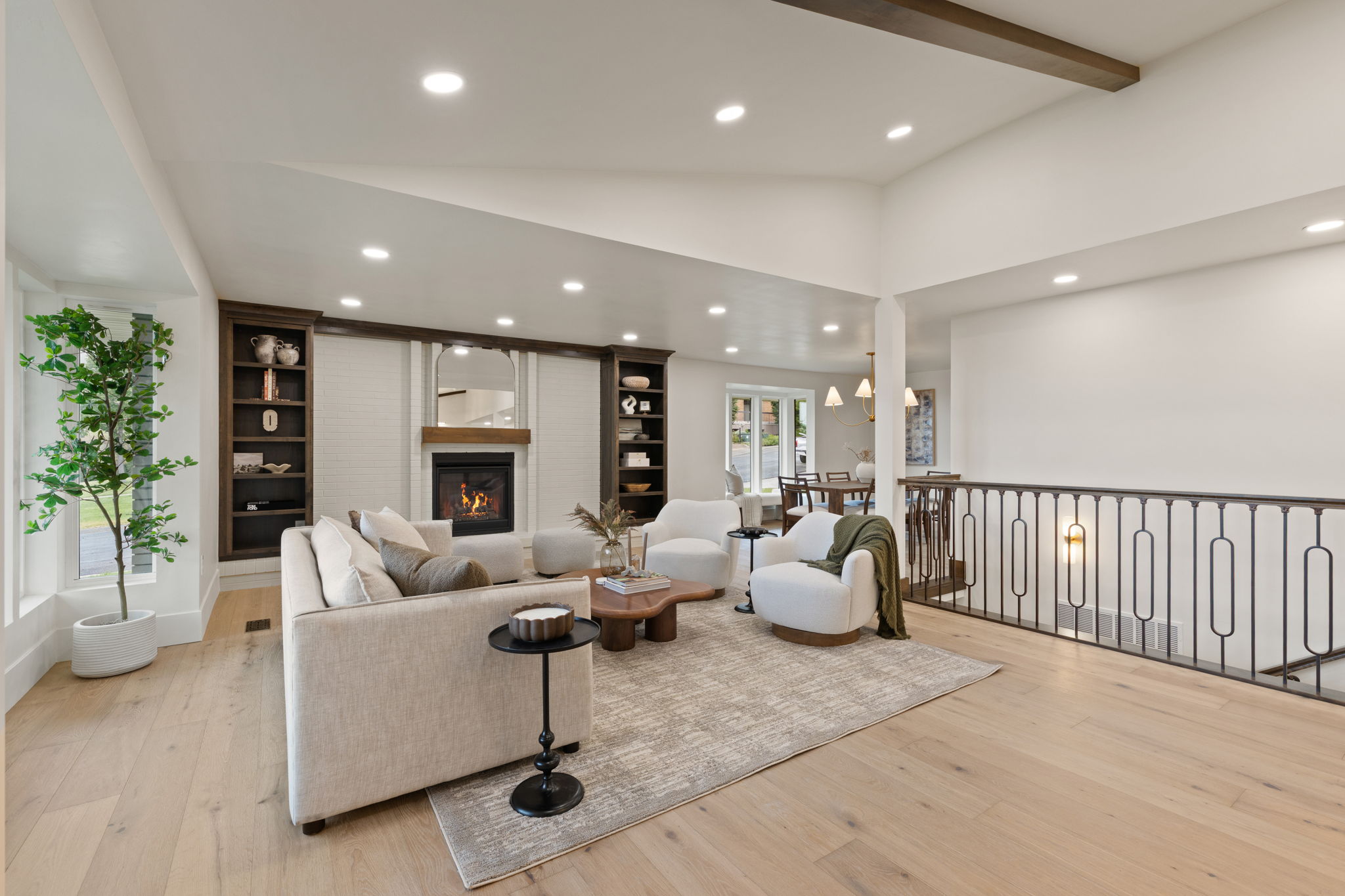 Spacious living area featuring light wood-finish flooring, recessed lighting, a fireplace with a wood mantle, and built-in shelving