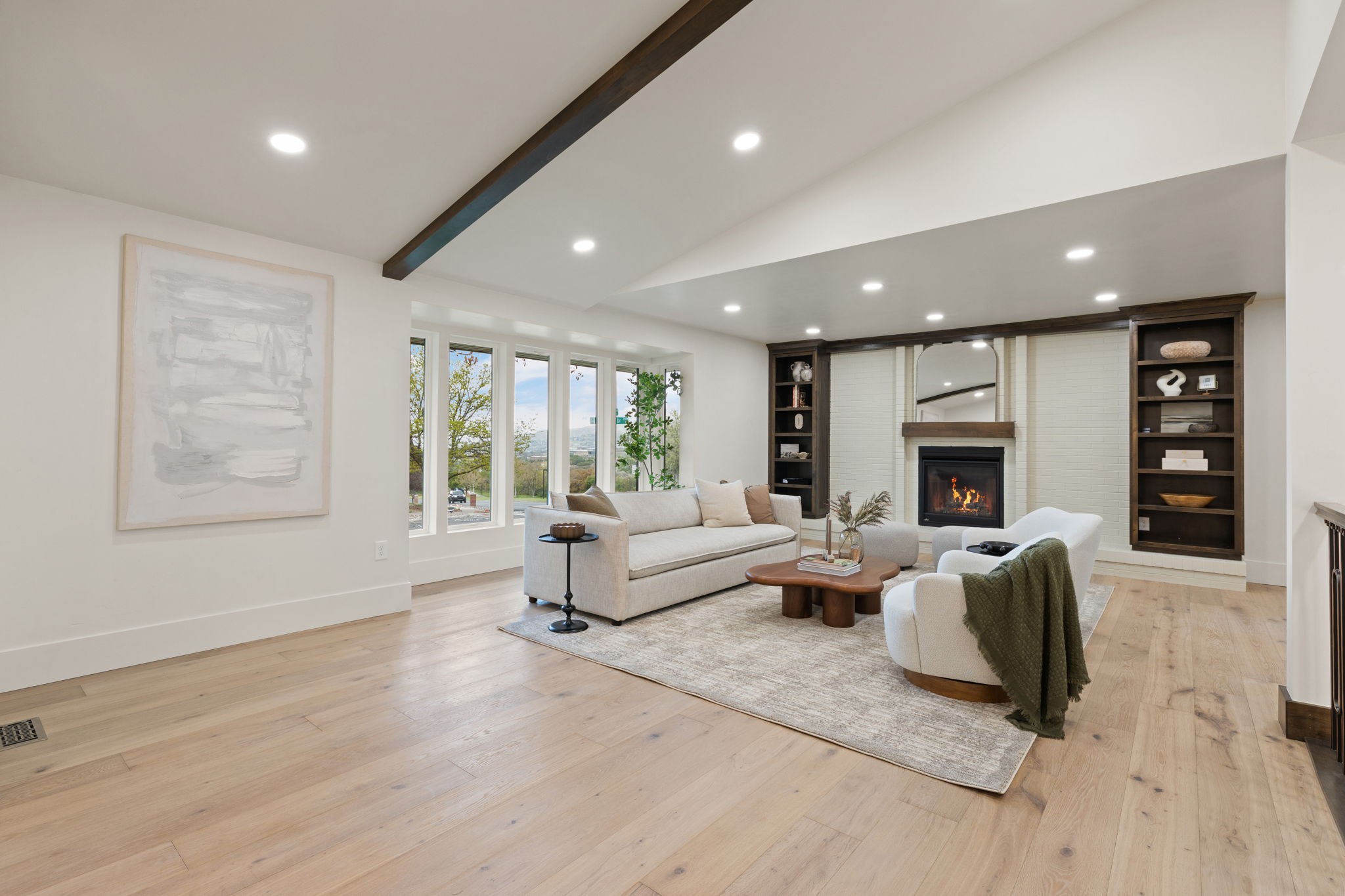 Vaulted ceiling featuring a dark wood beam, recessed lighting, and light wood-finish flooring