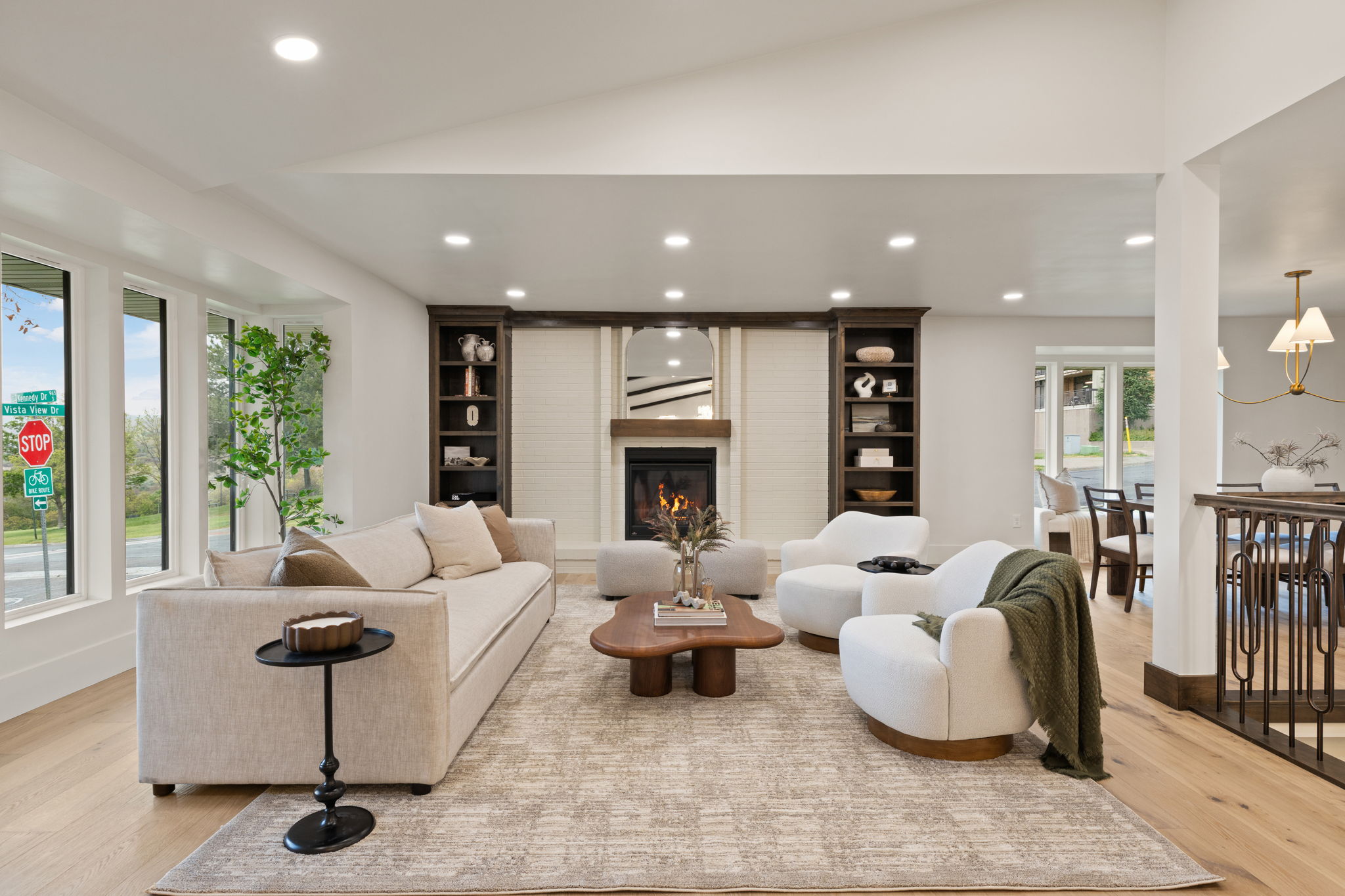 Spacious living area featuring light wood-finish flooring, recessed lighting, and a prominent fireplace with a substantial mantelpiece