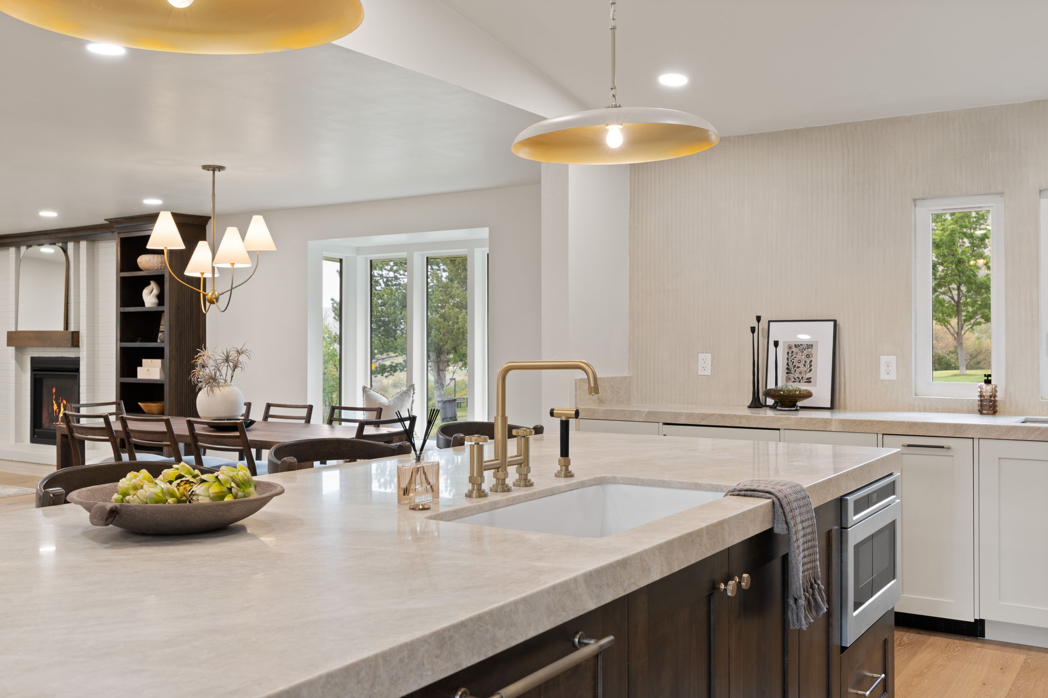 Kitchen island featuring a built-in sink with a gold-tone faucet, stone countertops, and integrated microwave