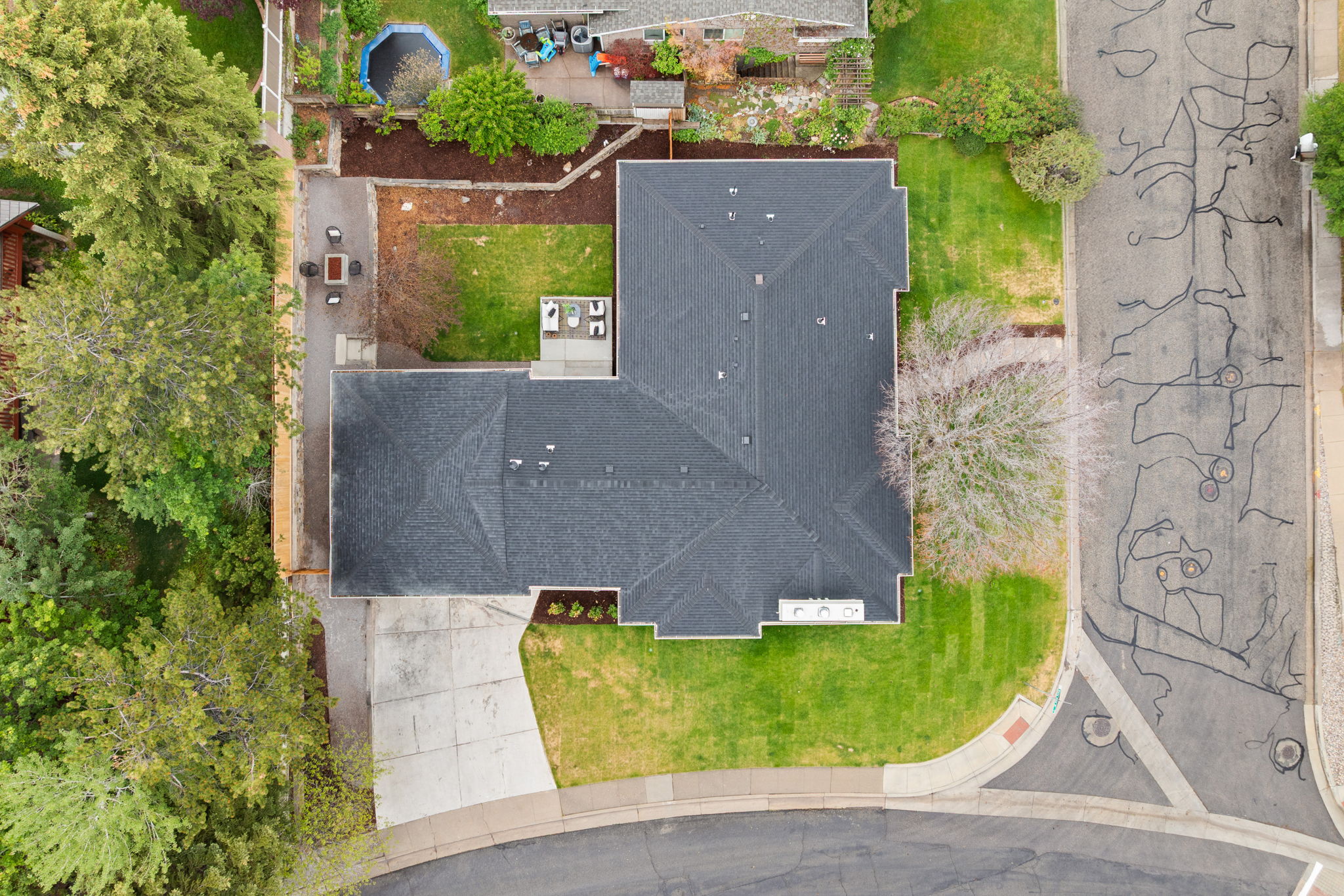 Expansive property featuring a dark shingle roof, concrete driveway, and a manicured lawn