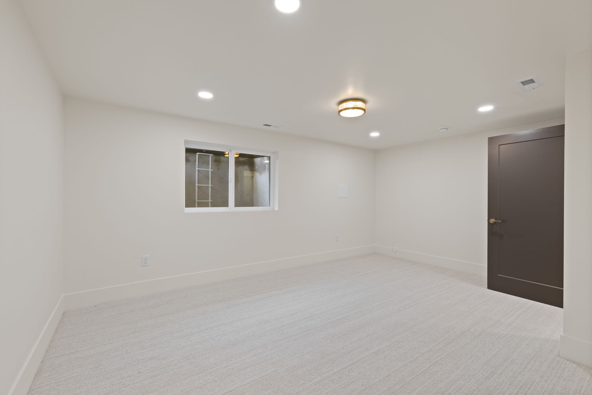 Bright interior room featuring light-toned carpeting, white walls, and recessed ceiling lighting