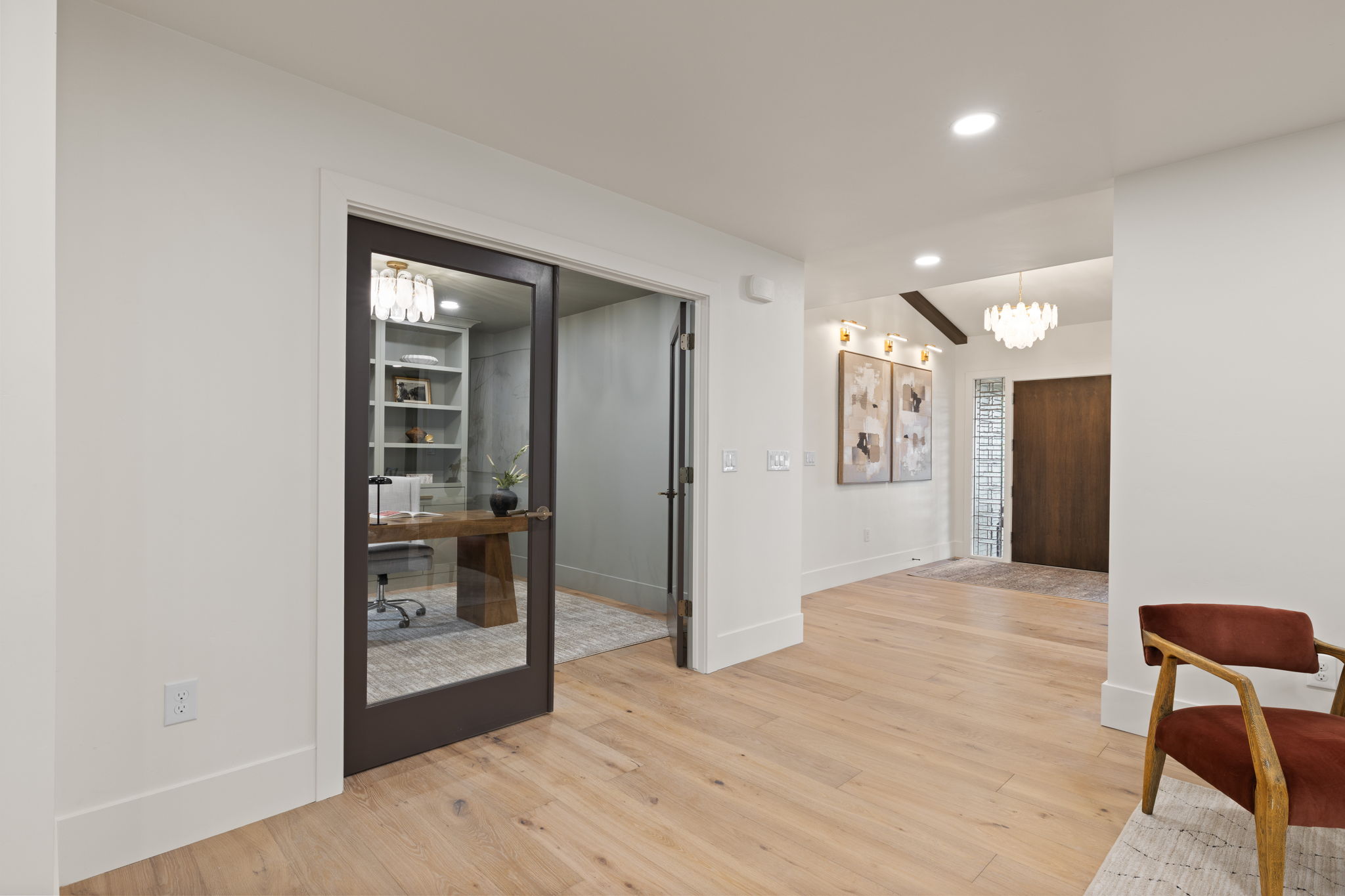 Light wood-finish flooring throughout, with a glass-paneled office entry door featuring built-in shelving
