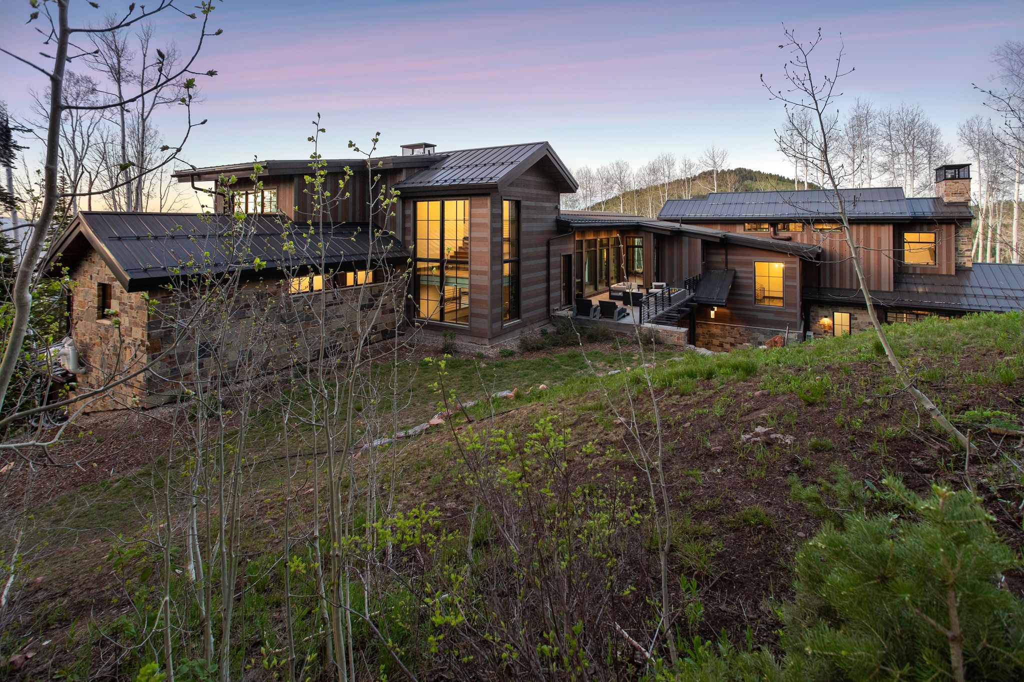Modern mountain residence featuring a multi-level design with extensive dark wood siding and stone accents
