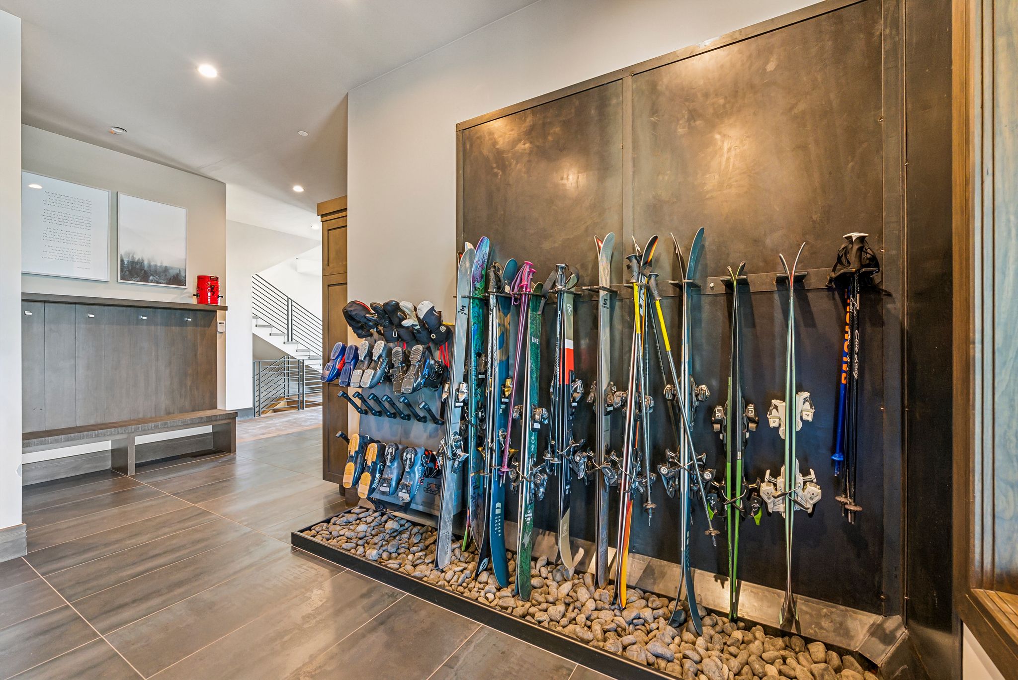 Dedicated ski and boot storage system with a dark metal panel backdrop and river rock base