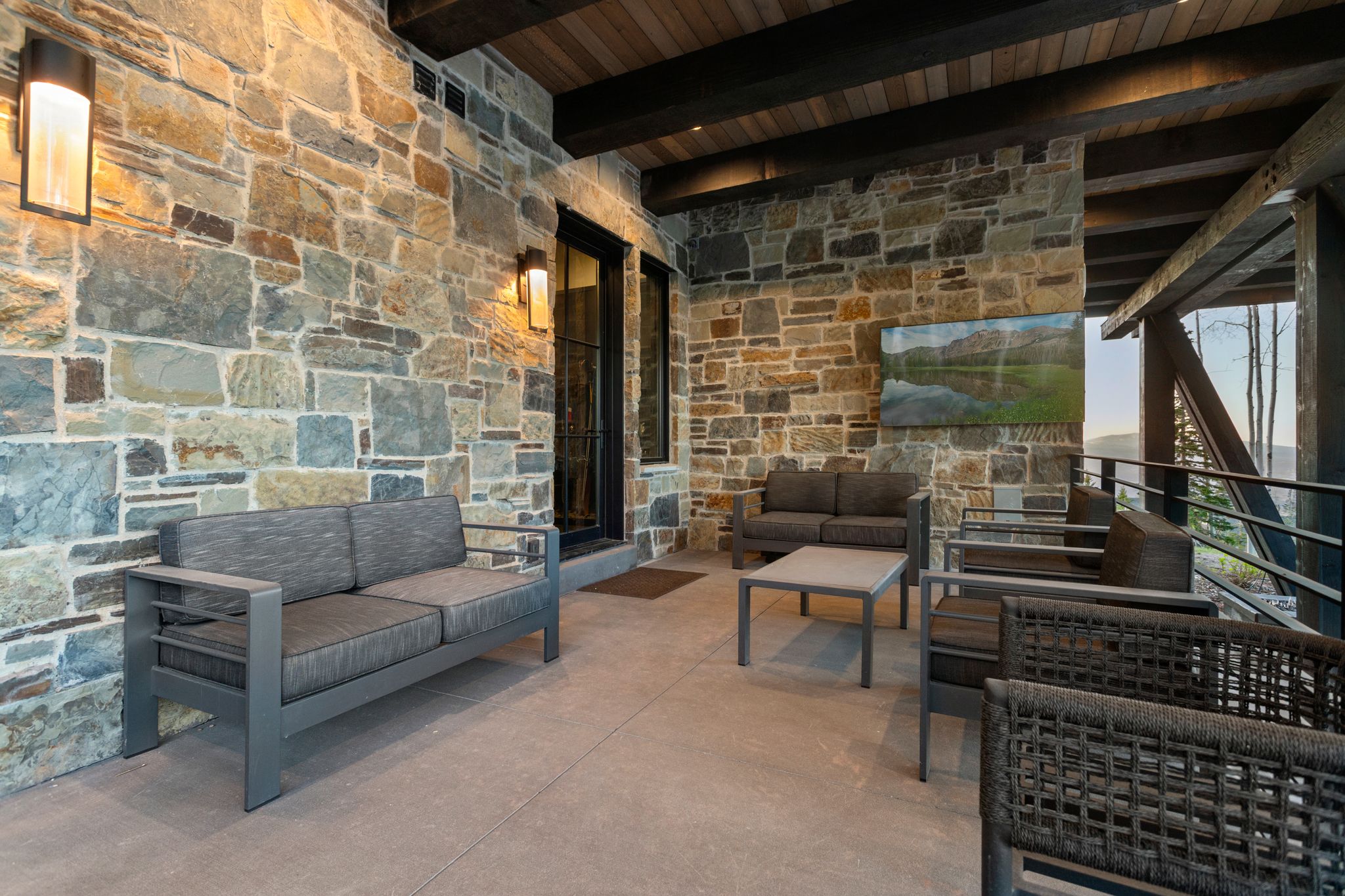 Expansive covered patio featuring a stone-clad wall, wood plank ceiling, exposed wooden beams, and recessed lighting