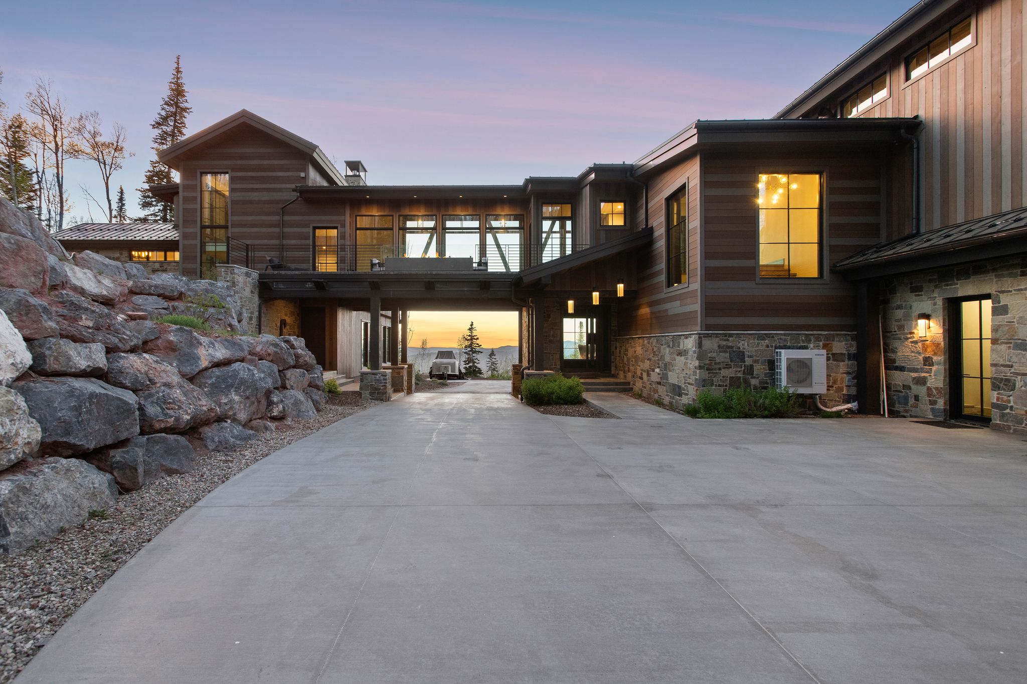 Contemporary residence featuring a multi-level design with a concrete driveway and stone retaining wall