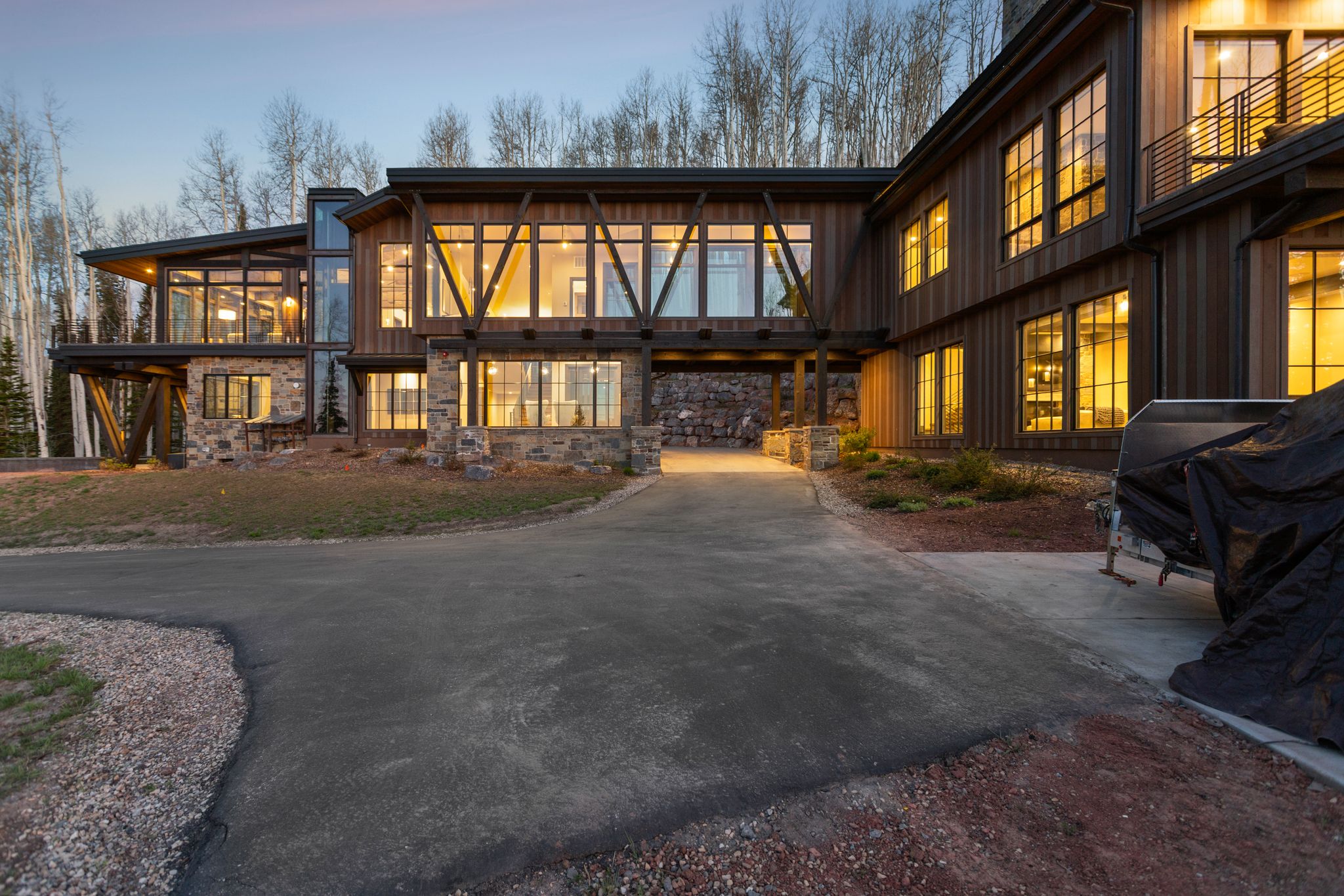 Modern architectural residence featuring extensive glazing, stone accents, wood siding, and multiple balconies
