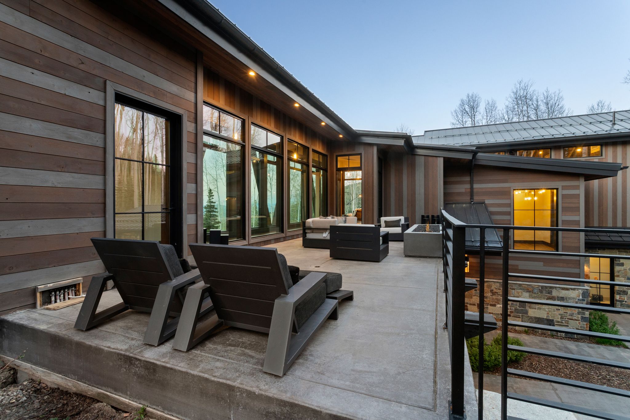 Expansive concrete patio with contemporary dark wood-tone siding and large black-framed windows