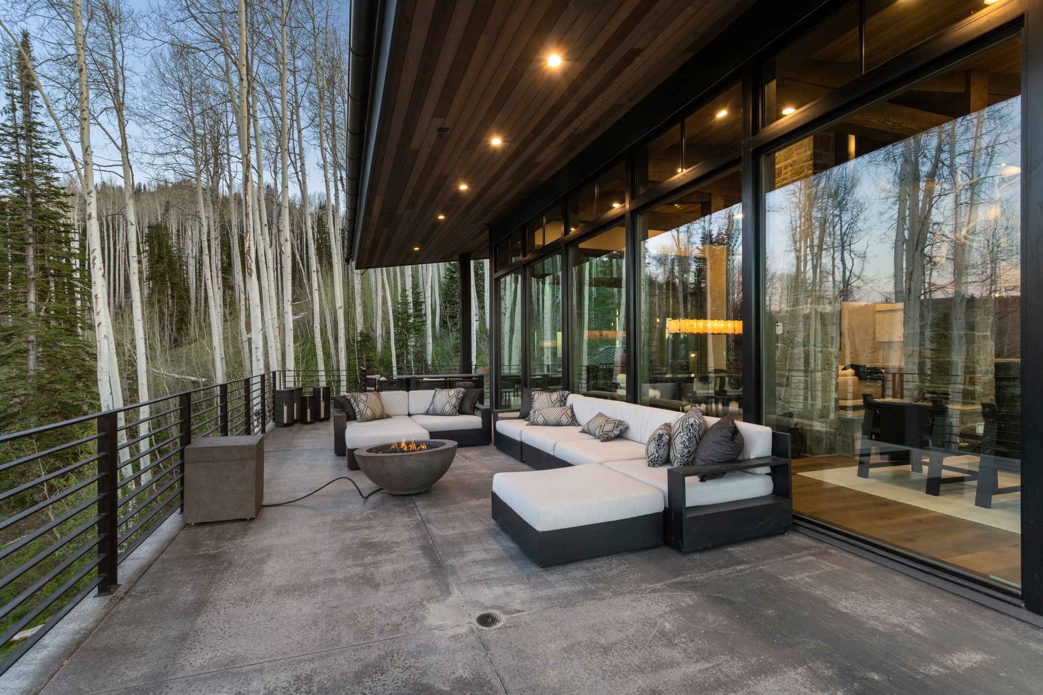 Expansive concrete patio with a built-in fire pit, surrounded by black metal railings