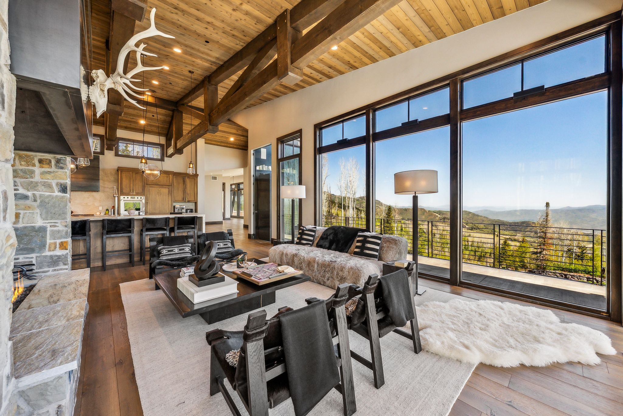 Expansive living area with a vaulted wood-plank ceiling, exposed wood beams, and a stone-clad fireplace