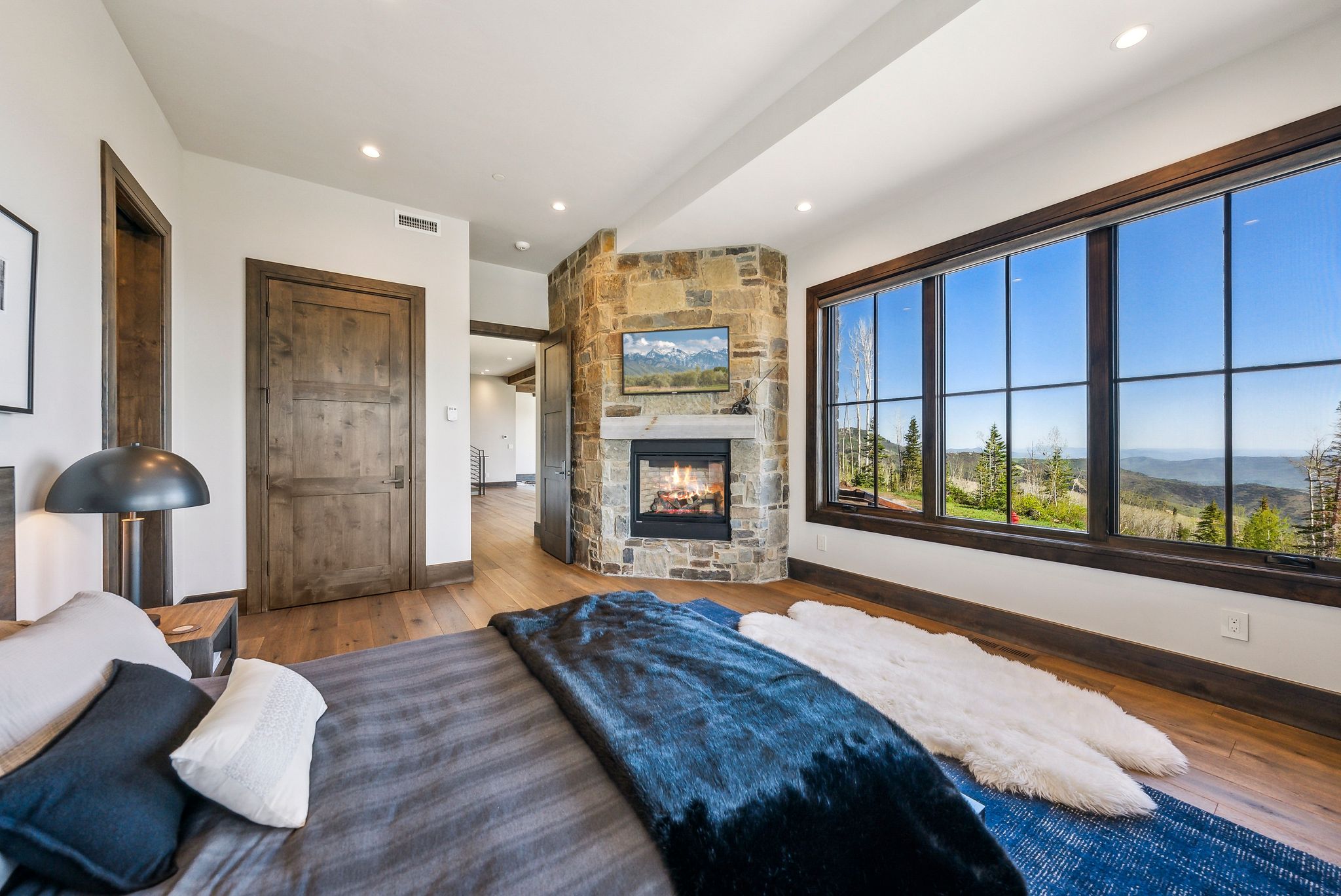 Expansive window wall with dark trim framing distant mountain and tree-lined scenery